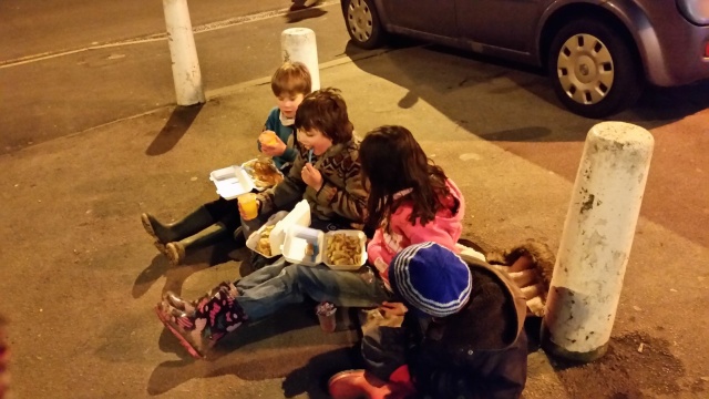 Four beaver scouts are having boxed meal on the street.